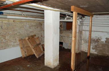 <p>De constructie van het kelderdek gaat schuil achter een later aangebracht houten plafond. De gemetselde onderslag en kolommen dragen waarschijnlijk de gangmuur. </p>

